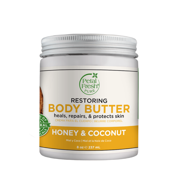 "Image of Petal Fresh Honey Coconut Oil Body Butter Restoring. The jar is open, revealing a rich, creamy body butter inside, with a light yellow color and a honeycomb pattern on the label. In the background, there are coconuts and honey, highlighting the natural ingredients used in the product.